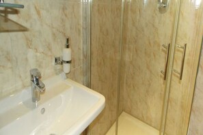 A bathroom with a white sink, a mirror, and a glass shower enclosure. - Jonaith Hotels & Suites (Lekki)