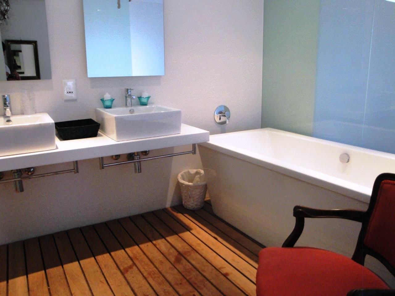 Une salle de bain avec deux lavabos, une baignoire et un plancher en bois.
