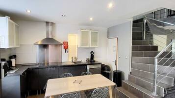 Una cocina moderna con una isla central, electrodomésticos de acero inoxidable y una escalera que sube a un nivel superior.