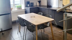 Eine moderne Küche mit Essbereich, ausgestattet mit einem Edelstahlkühlschrank, einer Kaffeemaschine und einem Herd.