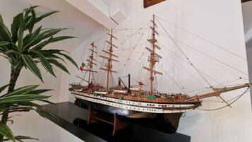 A model ship on display, surrounded by potted plants.