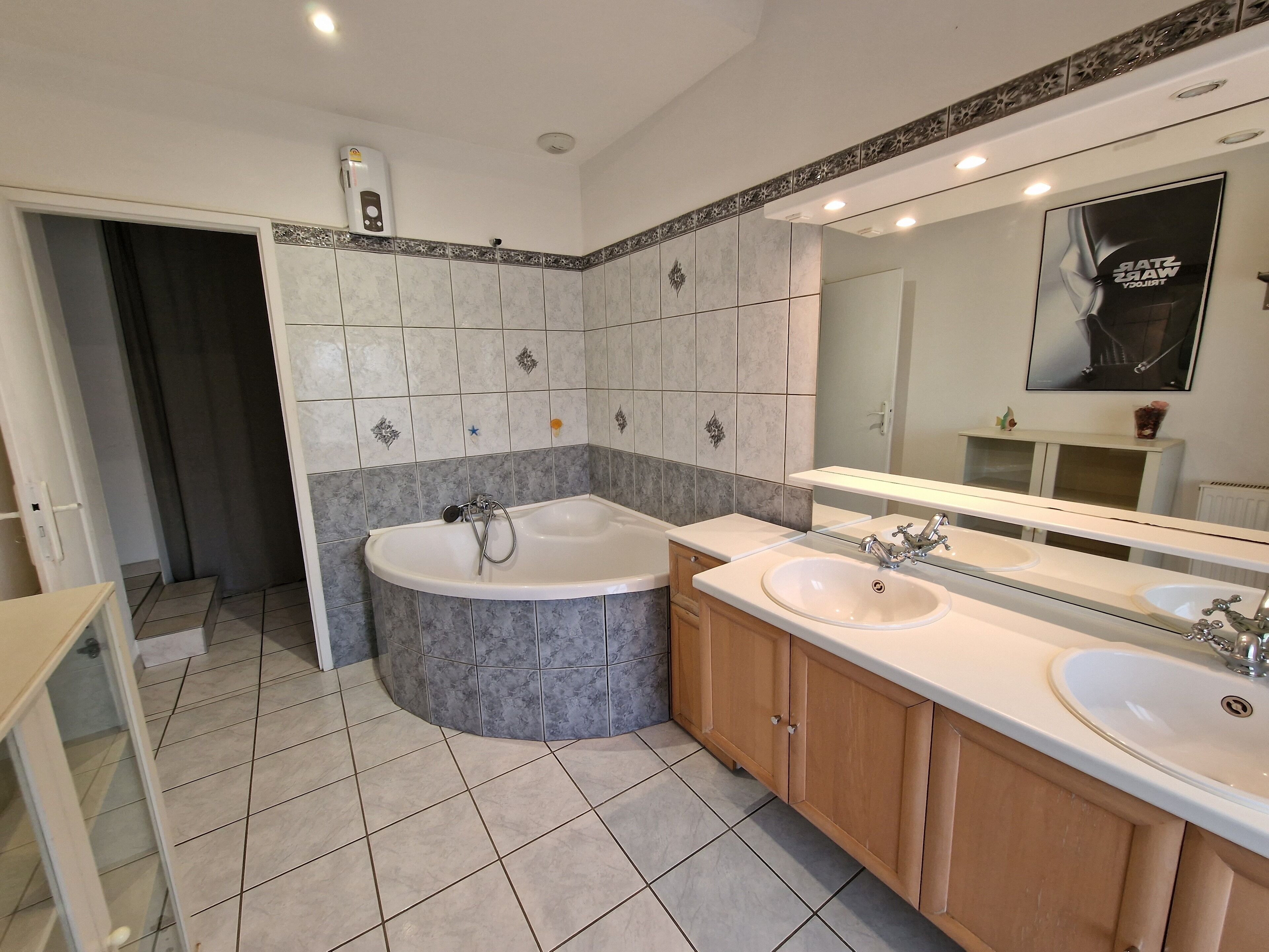 A modern bathroom with a bathtub, two sinks, and a large mirror.