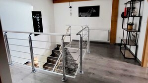 Eine Treppe mit Metallgeländern, einem Oberlicht, einem Zebra-Kunstwerk und einer schwarz-weißen Zibra-Tür.