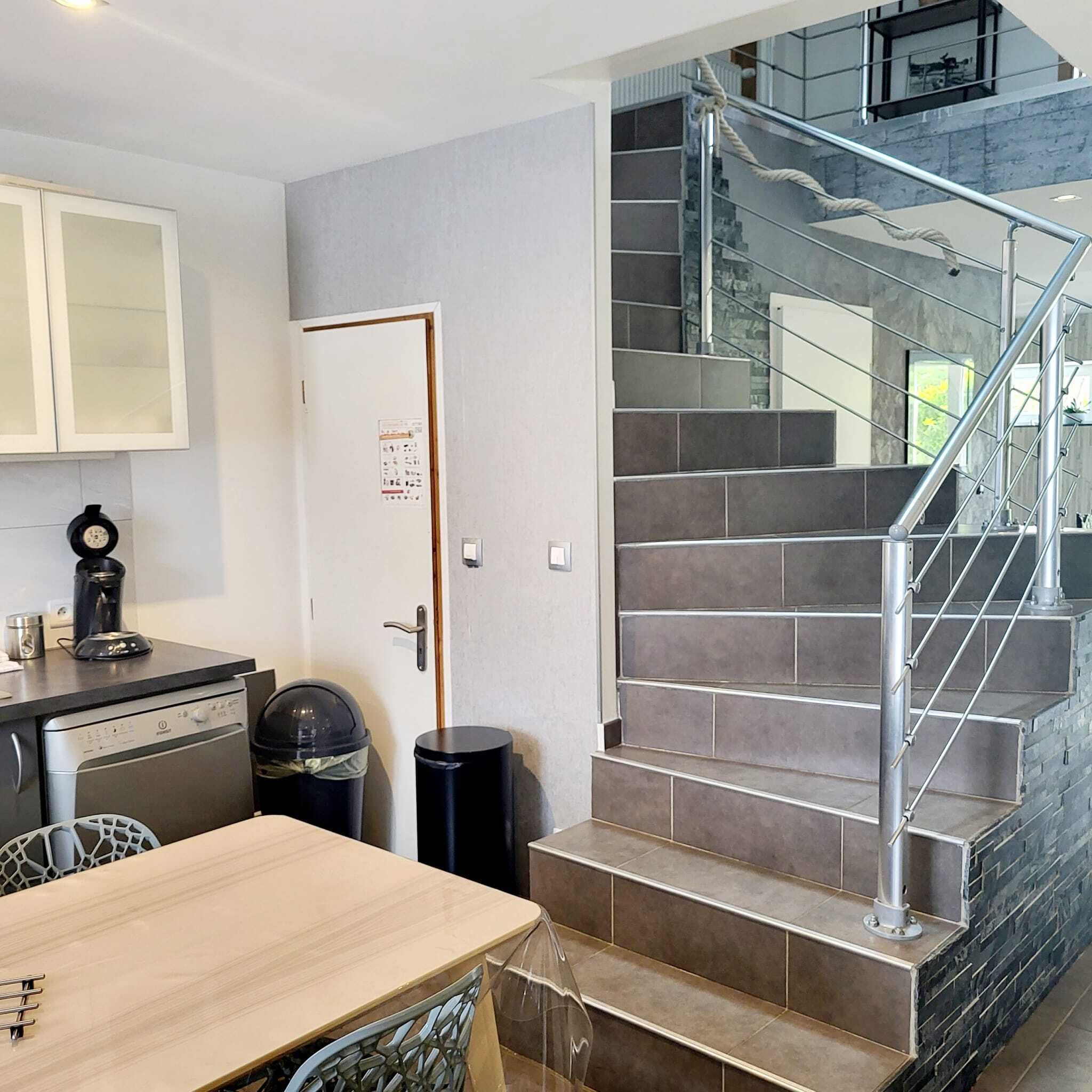 A modern kitchen with a dining table, a coffee machine, and a trash bin.
