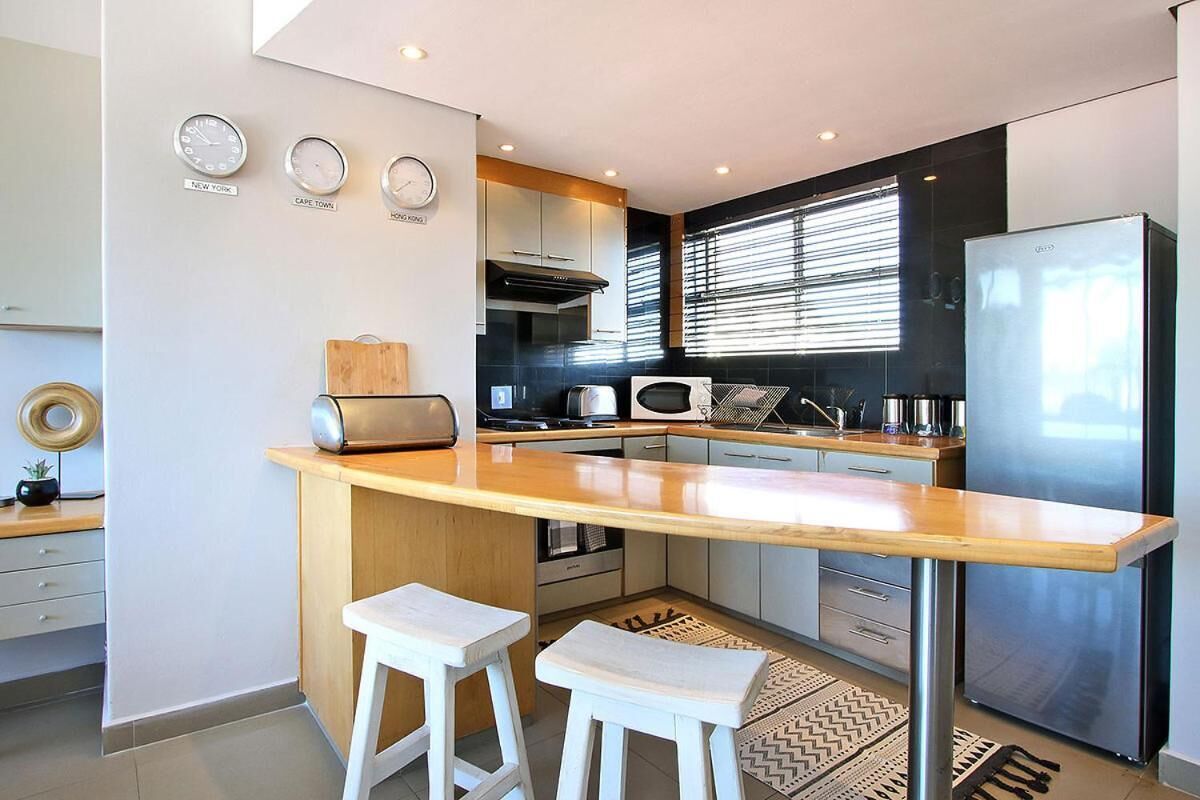 A modern kitchen with a central island, stainless steel appliances, and a built-in oven.