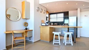 A compact kitchen with a wooden countertop, a microwave, and two stools. - Morakani (Cape Town)