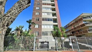 A multi-story building with a brick facade and multiple balconies. - Morakani (Cape Town)
