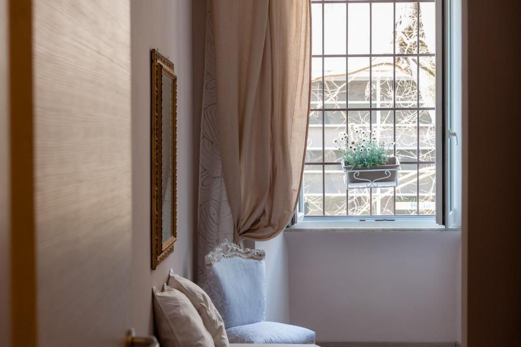 Une pièce avec une fenêtre, une chaise et une plante posée sur le rebord de la fenêtre.