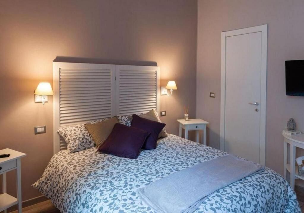 Ein Schlafzimmer mit einem Bett, zwei Nachttischlampen, einem Nachttisch, einem Fernseher und einer Tür.