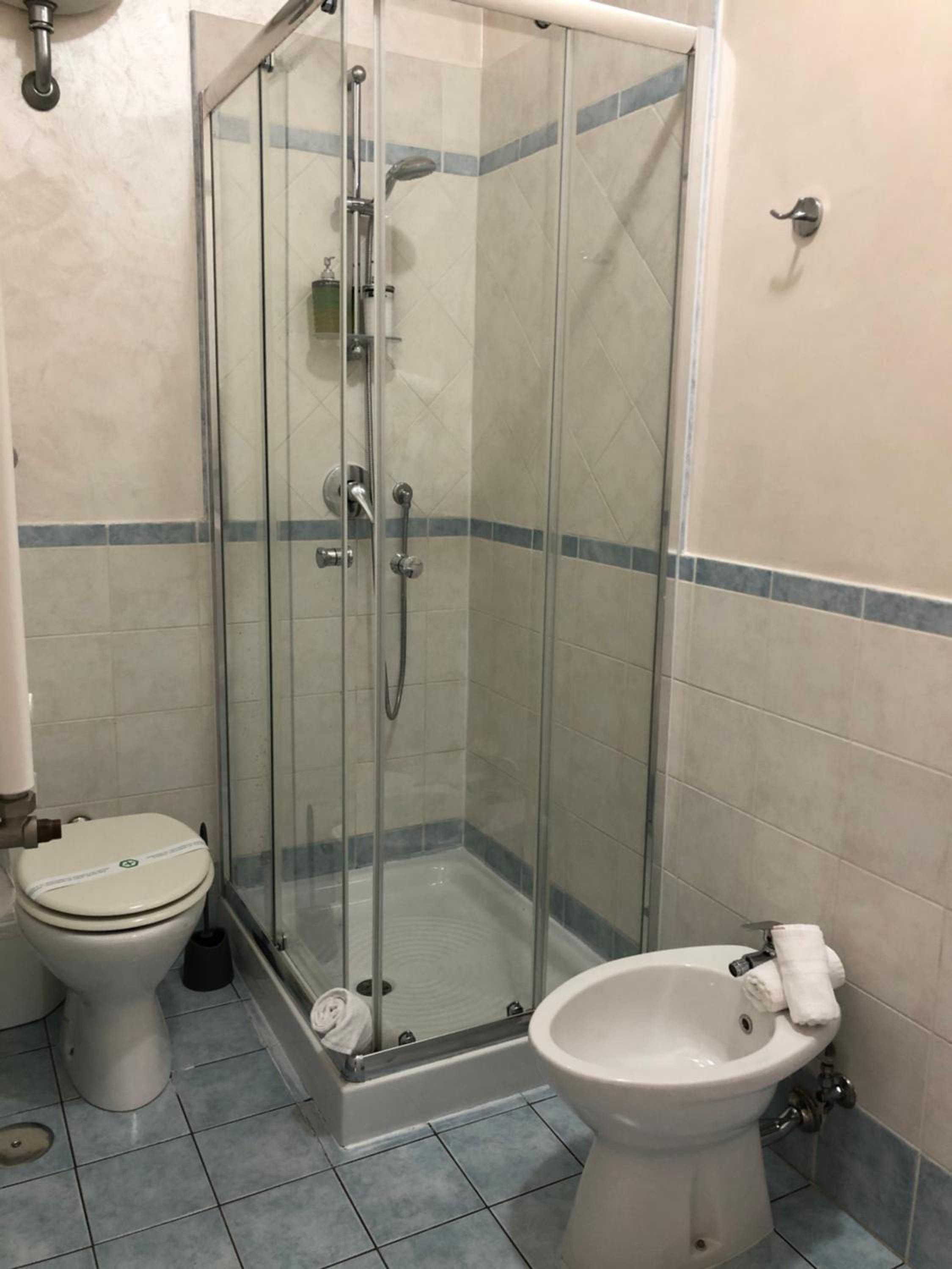 A bathroom with a glass-enclosed shower, a toilet, and a bidet.