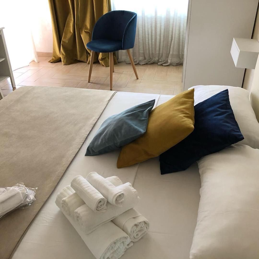 Una habitación de hotel con cama, almohadas, una silla y toallas enrolladas.