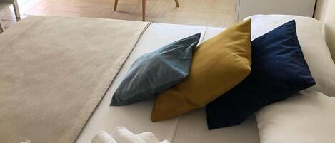 Una habitación de hotel con cama, almohadas, una silla y toallas enrolladas.