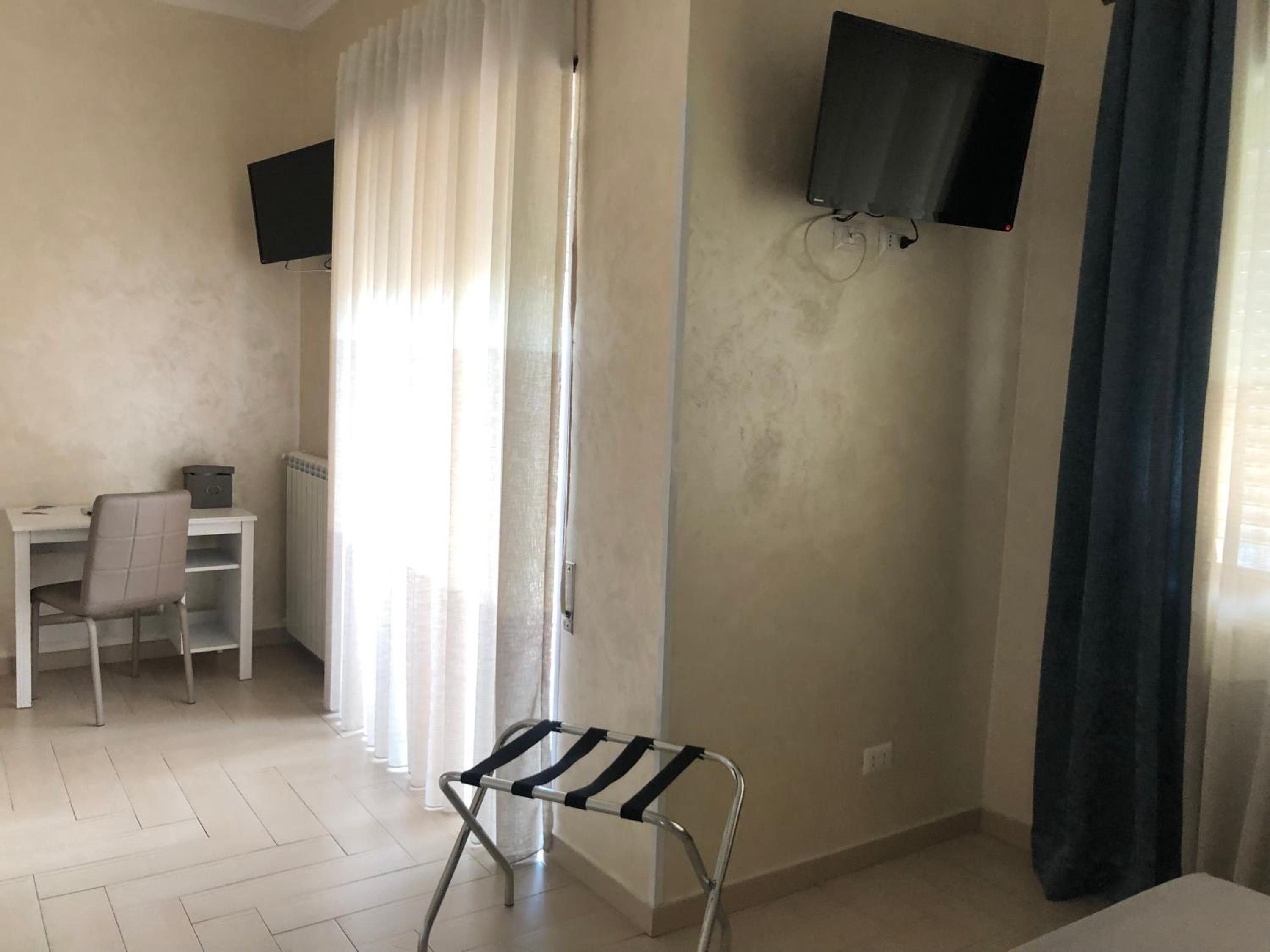 A room with a desk, chair, and a TV mounted on the wall.