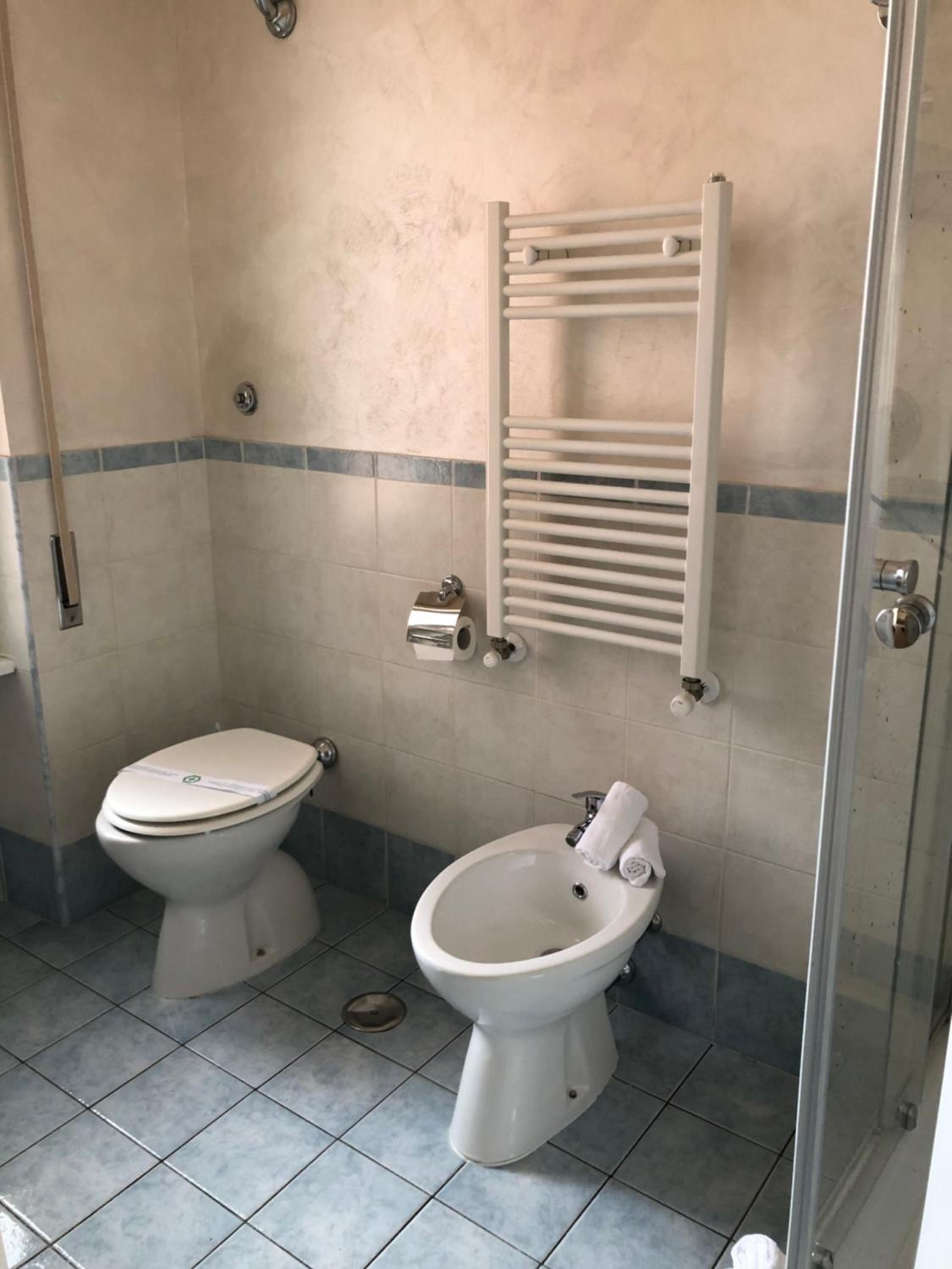 Un bagno con il water, un bidet e una cabina doccia in vetro.