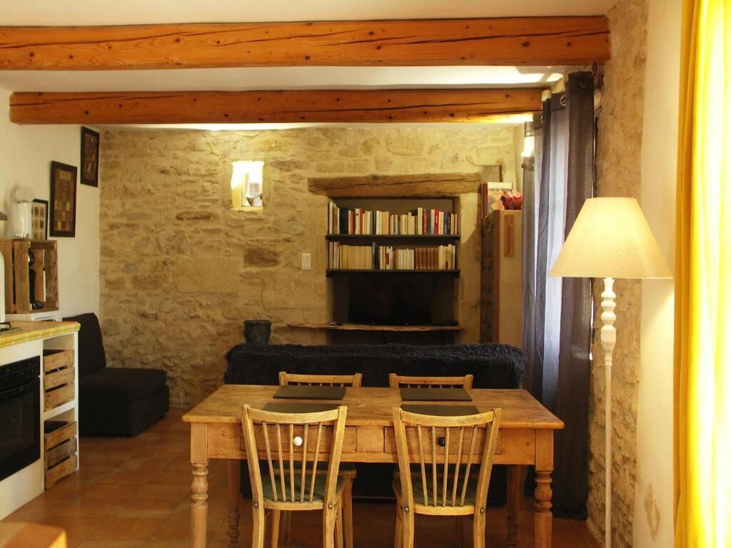 Une pièce chaleureuse avec une table à manger en bois, des chaises, une bibliothèque et un mur en pierre.