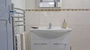 A bathroom with a white sink, a mirror above it, and a towel rack with a towel. - Birch at Somerhill (Hove)