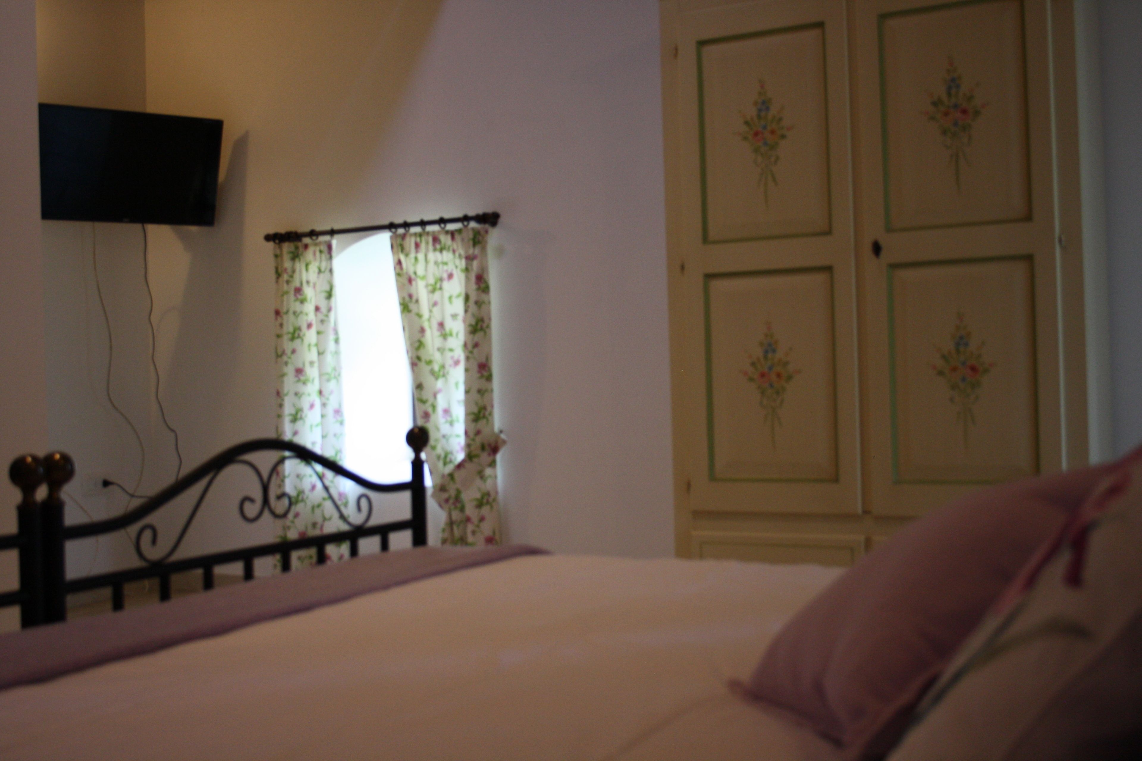 A bedroom with a bed, a TV mounted on the wall, and a door with floral decorations.