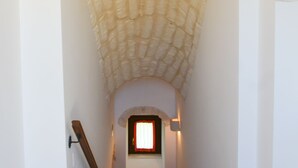 Un escalier étroit, avec un plafond en pierre et une petite fenêtre en haut.