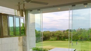 A modern kitchen with a large island, a ceiling fan, and a view of a golf course through large windows.