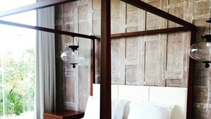 A four-poster bed with white linens and striped bedding, set against a wooden wall with a window and a nightstand with a lamp.