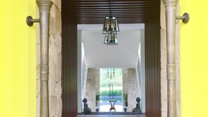 A hallway with patterned tiles, a hanging light fixture, and decorative columns.