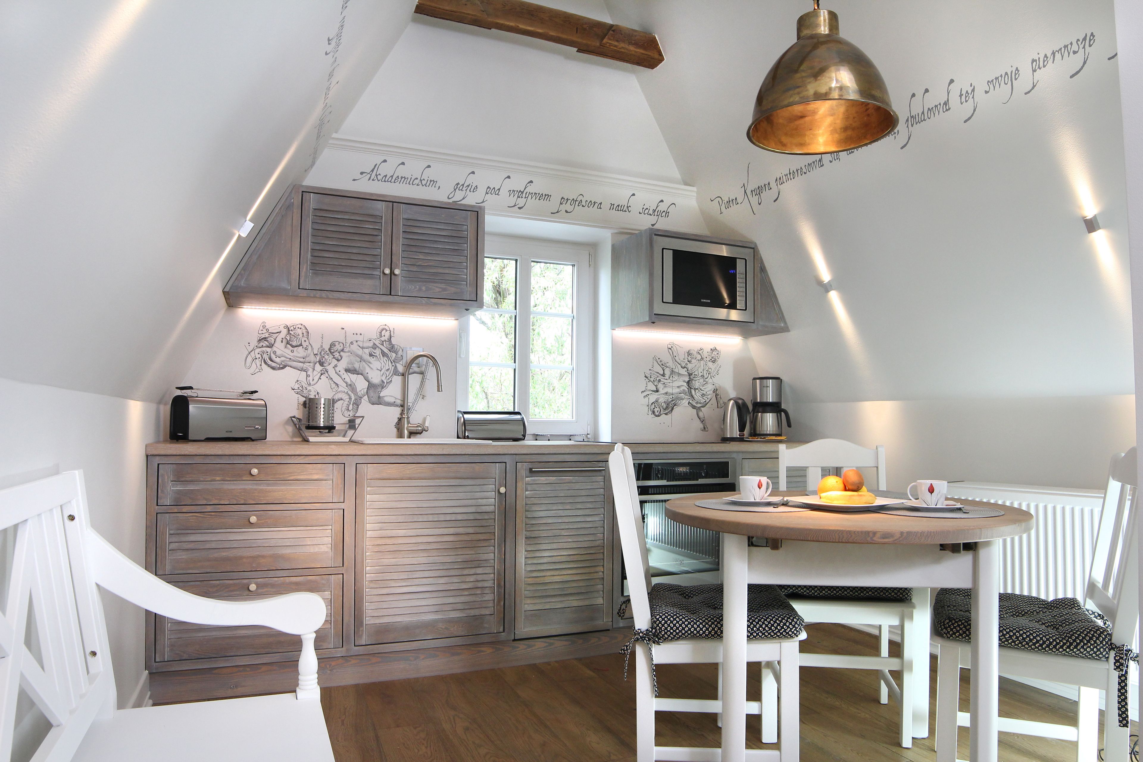 A kitchen with a wooden countertop, white cabinets, a microwave, and a dining area with a round table and white chairs.