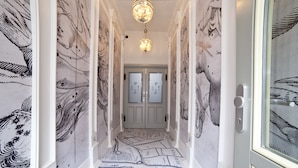 A hallway with patterned wallpaper, a chandelier, and a double door with frosted glass panels. - Patio Apartamenty (Gdansk)