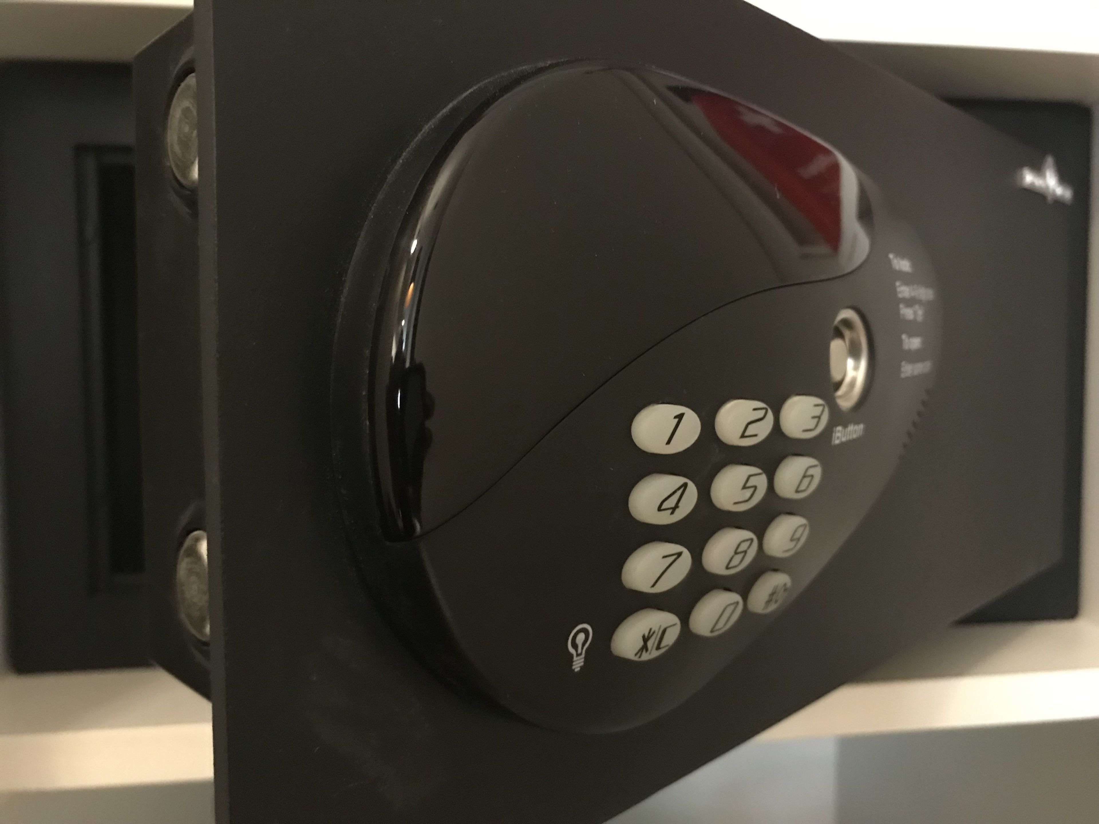 A black telephone keypad with white buttons and a red emergency button.