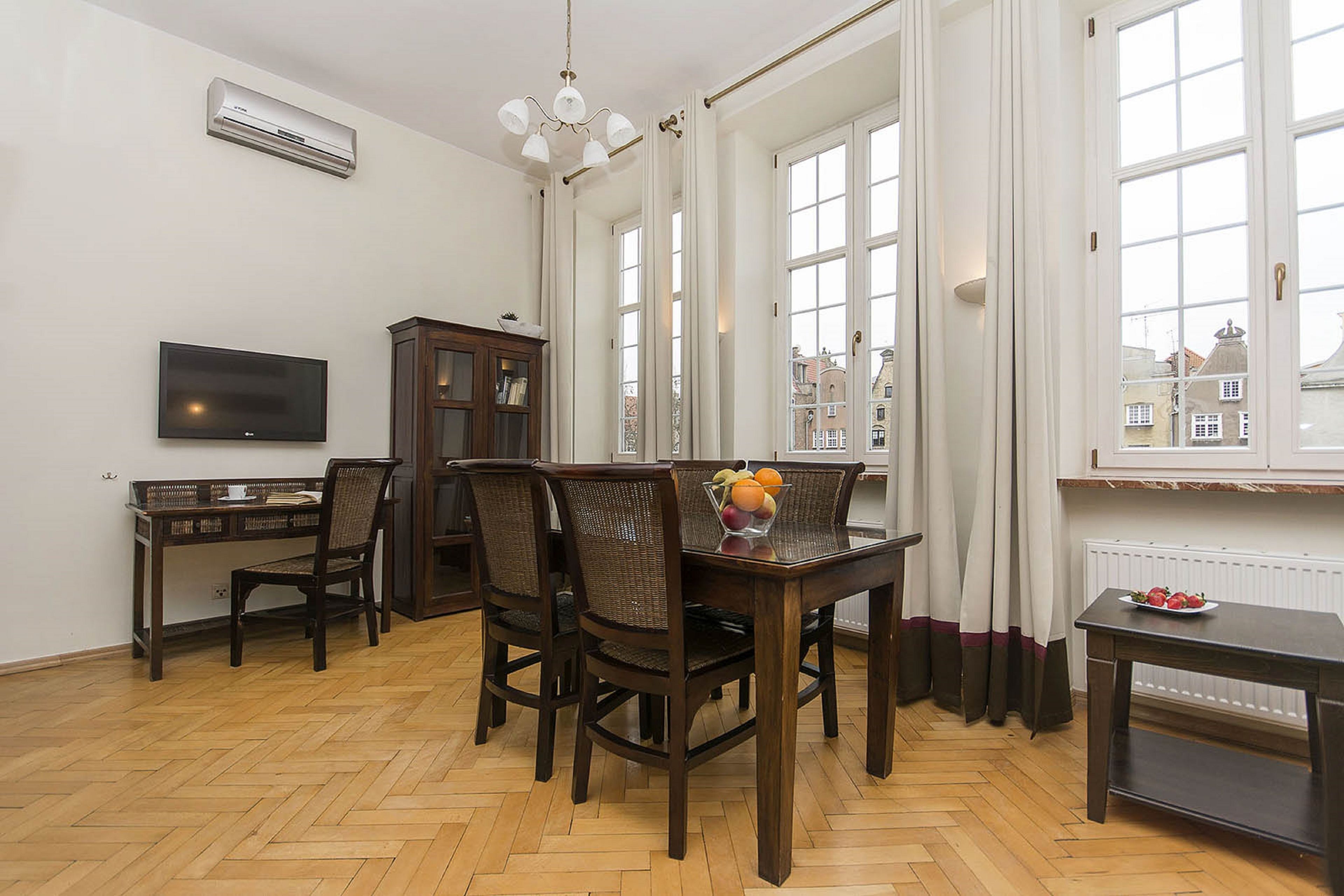 A dining area with a wooden table, four chairs, a television, and a cabinet.