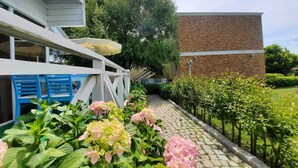Un sendero en un jardín, con un muro de ladrillo y un edificio blanco con barandilla azul.