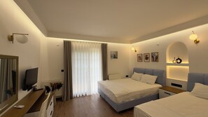 A hotel room with two beds, a TV, a desk, and a window with curtains.