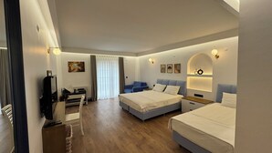 Habitación de hotel con dos camas, un escritorio con silla, televisor y ventana con cortinas.