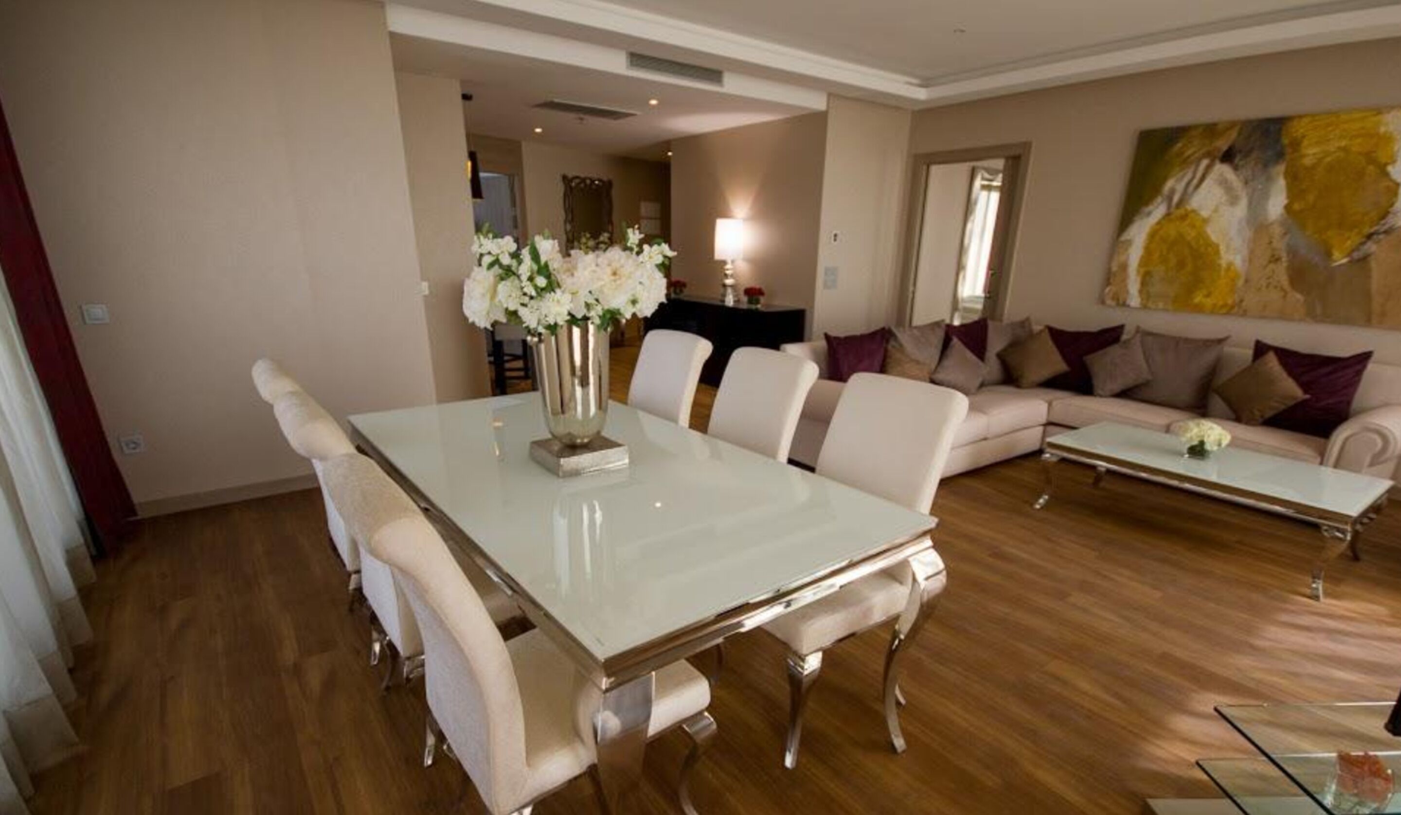 A spacious living room with a large white dining table, comfortable seating, and a modern sofa.