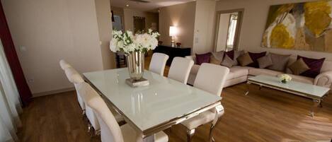 A spacious living room with a large white dining table, comfortable seating, and a modern sofa.