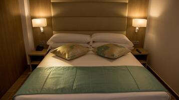 Una habitación de hotel con una cama grande, dos lámparas de noche y un cabecero de madera.