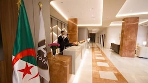 A hotel reception area with a marble floor, reception desk, and flags. - Az Hotel Le Zephyr Mostaganem (Mazagran)