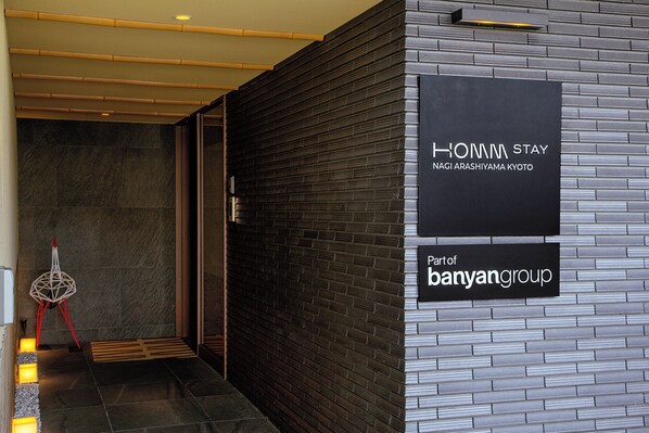 A modern hotel entrance with a sign for Honnami Stay in Nagi Arashiyama Kyoto. - Homm Stay Nagi Arashiyama Kyoto By Banyan Group (Kyoto)