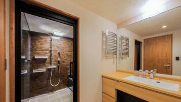 A modern bathroom with a glass-enclosed shower, wooden vanity, and a large mirror.