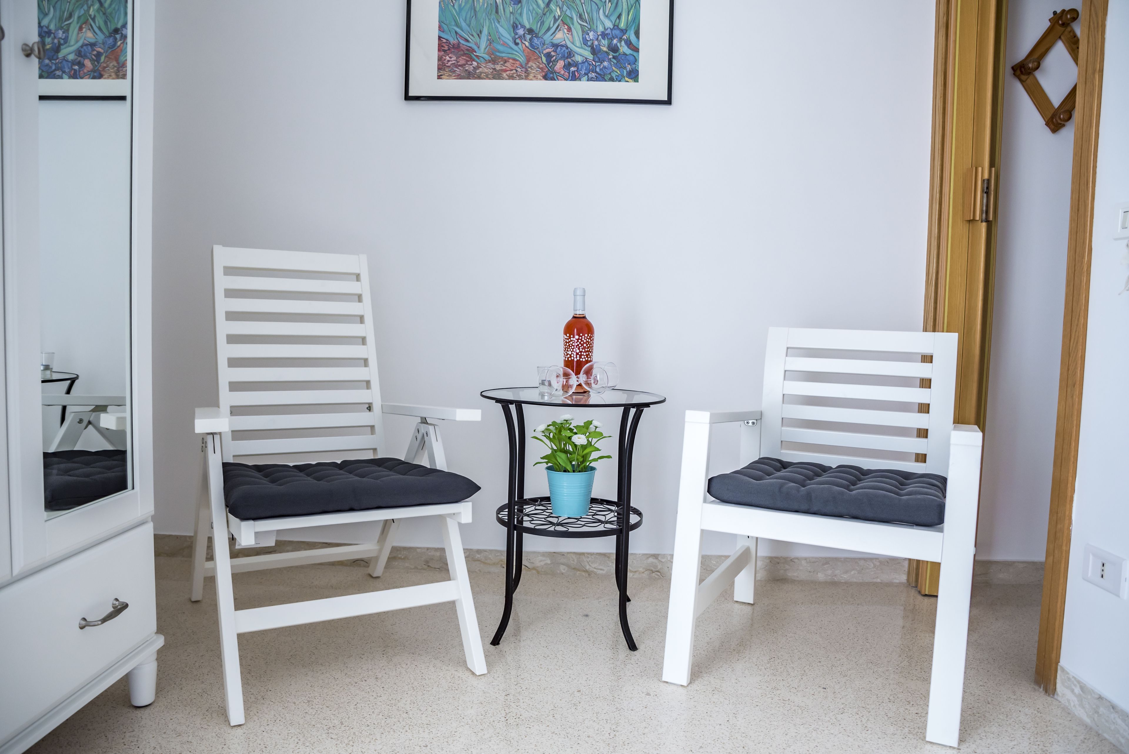 A small room with two white chairs, a small round table, and a potted plant.