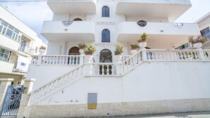 A white building with a central staircase, multiple balconies, and potted plants. - Appartamenti Albero di Giada (Polignano a Mare)