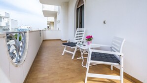A balcony with two white chairs and a small table, a potted plant, and a view of buildings in the background. - Appartamenti Albero di Giada (Polignano a Mare)