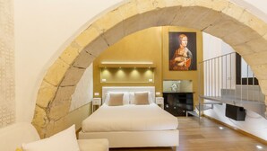 Un dormitorio con una cama grande, un sofá, un techo abovedado de piedra y un cuadro en la pared.