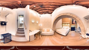 Una habitación amplia con techo de madera, una escalera, un sofá y un escritorio.