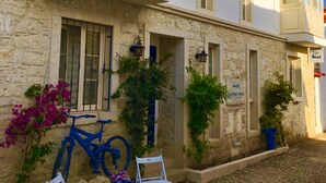 A two-story building with a stone facade, a tiled roof, and a sign indicating it is a boutique hotel. There are outdoor seating arrangements and potted plants. - Alacati Umitev Hotel (Cesme)