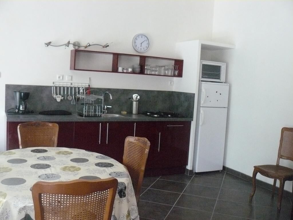 Una cocina compacta con comedor, un reloj y un microondas.