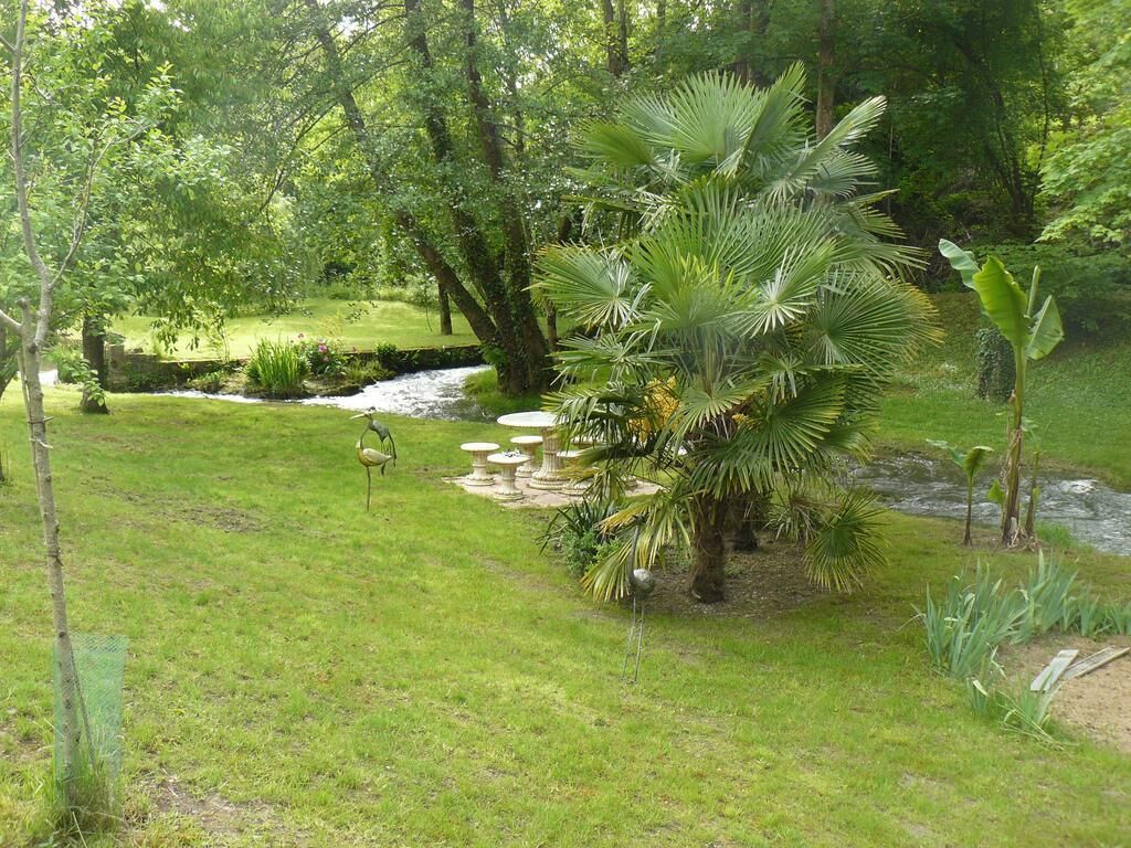 Een weelderige tuin met een vijver, palmbomen en een beeld van een vogel.