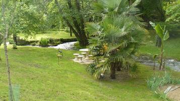 Un jardin luxuriant avec un petit étang, des palmiers et une statue d’oiseau.