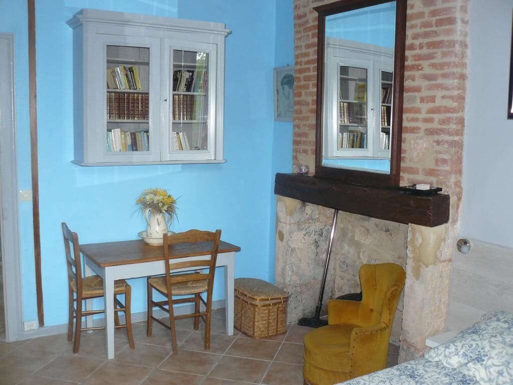 Una stanza con un tavolo da pranzo, sedie, una libreria e una finestra con vista.