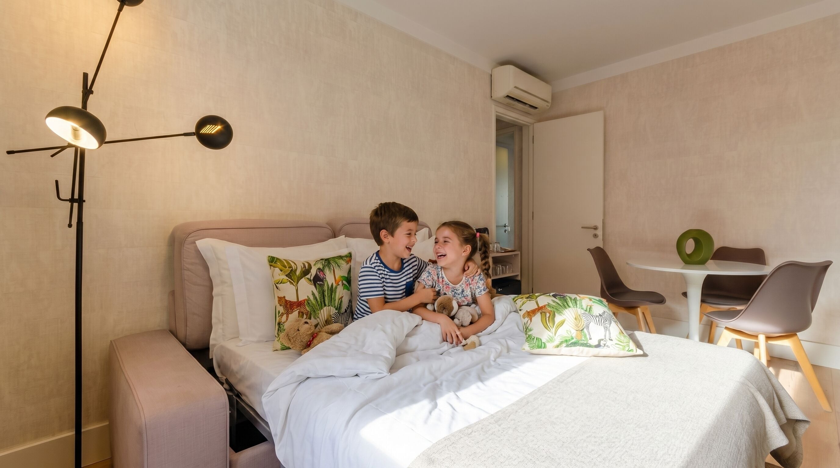 A bedroom with a bed, bedside lamp, and a small table with chairs.