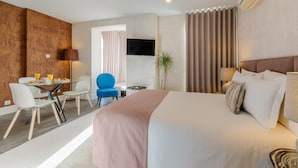 Una habitación de hotel moderna con una cama grande, un escritorio con sillas, un televisor y una planta.